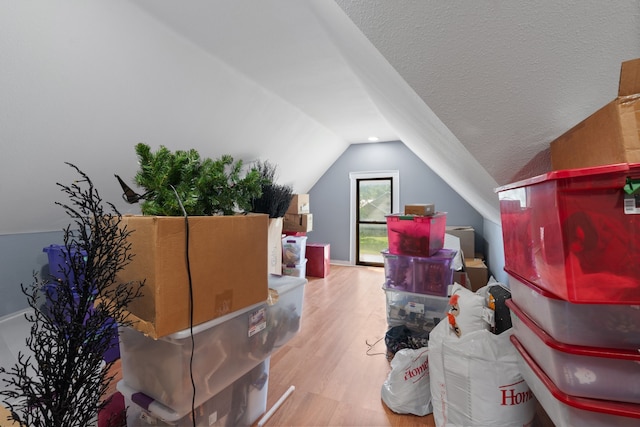 bonus room with a textured ceiling, vaulted ceiling, and wood-type flooring