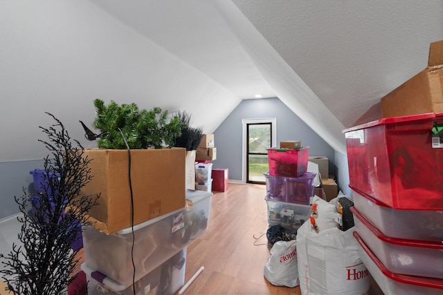 additional living space featuring lofted ceiling, a textured ceiling, and wood finished floors