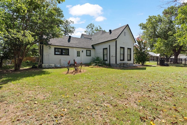 rear view of house with fence and a lawn