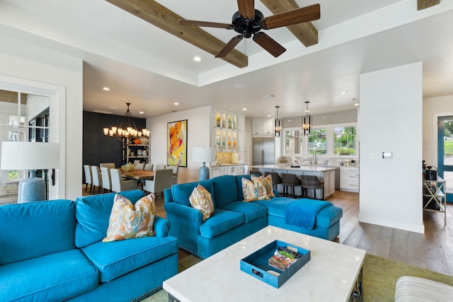 living room with ceiling fan with notable chandelier and hardwood / wood-style floors