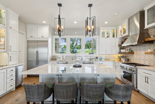 kitchen with backsplash, high quality appliances, a kitchen island, and wall chimney exhaust hood