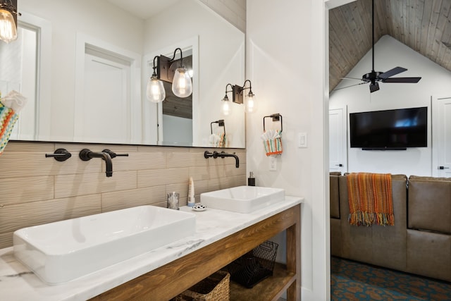 bathroom featuring lofted ceiling, double vanity, ceiling fan, tile walls, and tile patterned floors