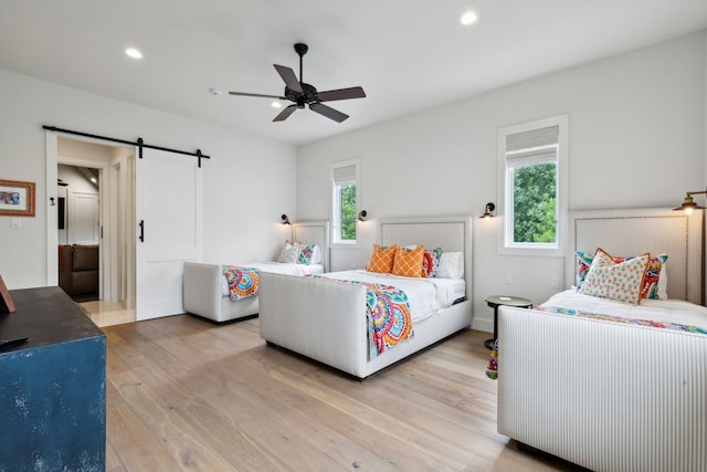 bedroom featuring light wood-type flooring, multiple windows, and a barn door