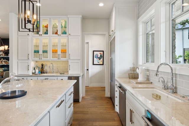 kitchen with decorative light fixtures, hardwood / wood-style flooring, white cabinets, sink, and backsplash