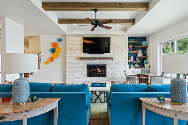 living room featuring built in features, a fireplace, beamed ceiling, and ceiling fan