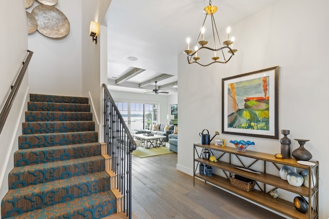 staircase with beamed ceiling, wood-type flooring, and ceiling fan with notable chandelier