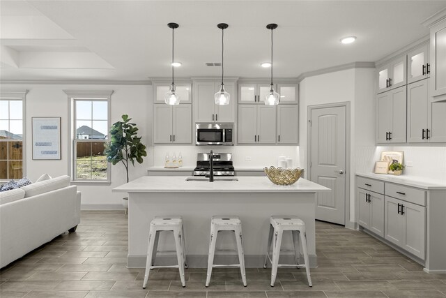 kitchen featuring hanging light fixtures, sink, a kitchen island with sink, white cabinetry, and stainless steel appliances