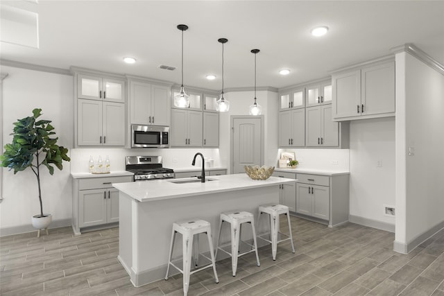 kitchen featuring stainless steel appliances, a center island with sink, light wood-type flooring, and sink