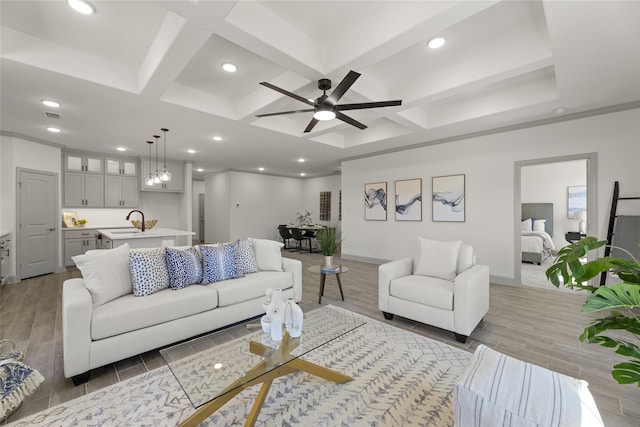 living room featuring light hardwood / wood-style floors, coffered ceiling, ceiling fan, and beamed ceiling