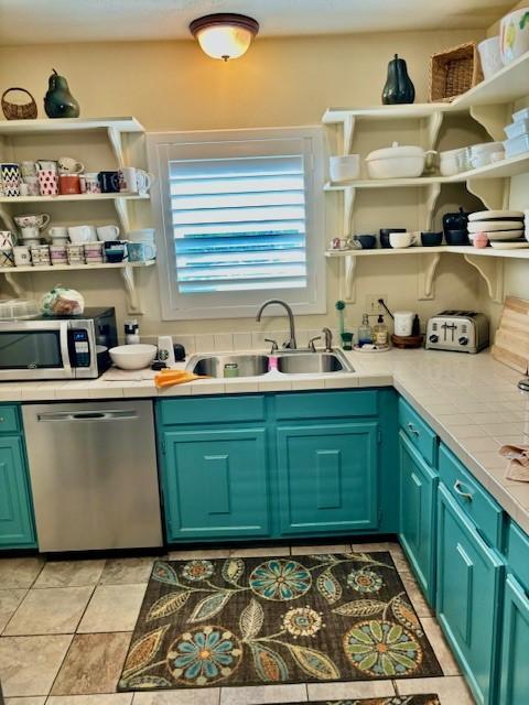 kitchen with sink, light tile patterned floors, and appliances with stainless steel finishes