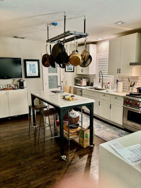 kitchen featuring sink, appliances with stainless steel finishes, white cabinetry, tasteful backsplash, and dark hardwood / wood-style flooring