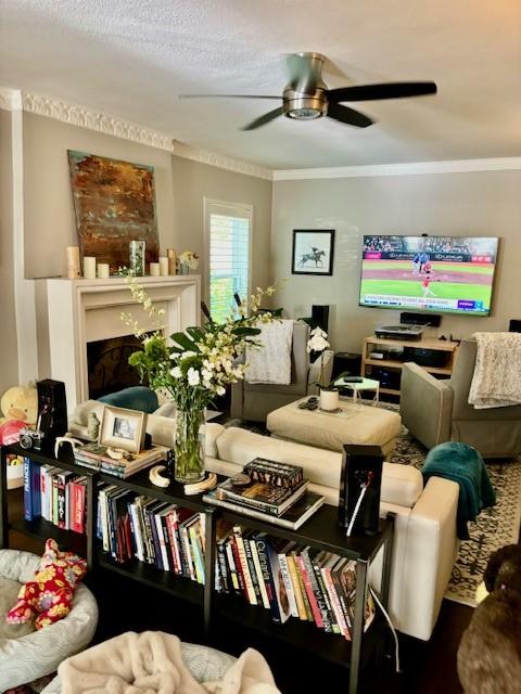 living room with a textured ceiling, ornamental molding, and ceiling fan