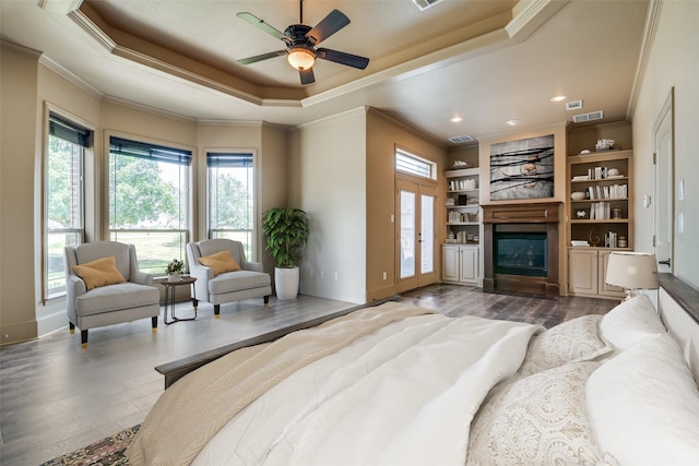 bedroom featuring ceiling fan, wood-type flooring, ornamental molding, and a raised ceiling