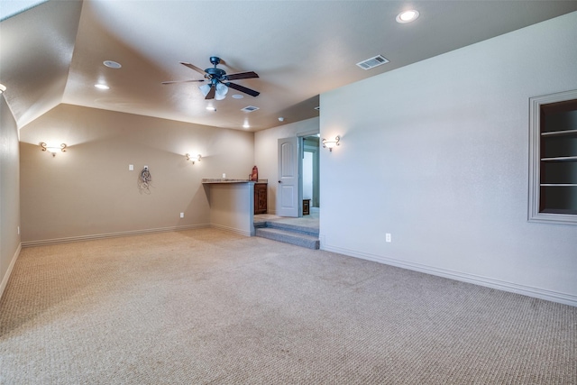 unfurnished living room with ceiling fan, light colored carpet, and vaulted ceiling