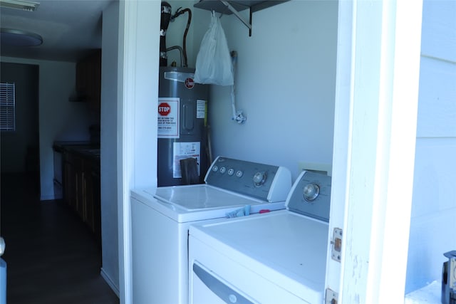 laundry area featuring washing machine and clothes dryer, dark wood-type flooring, and electric water heater