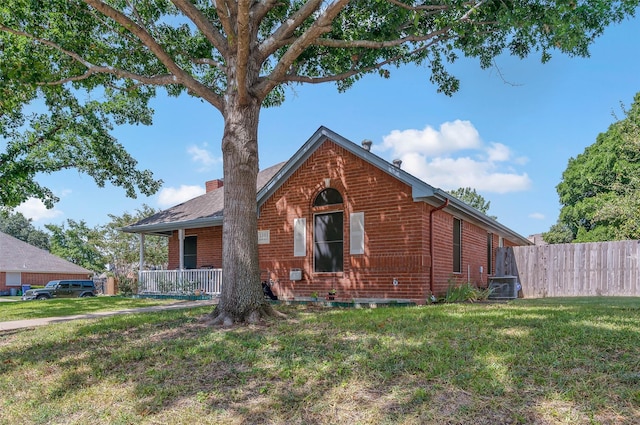 view of front facade with brick siding, a chimney, a front lawn, and fence