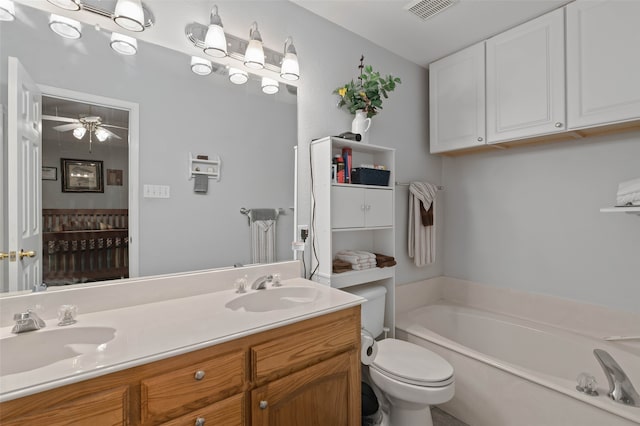 bathroom featuring double vanity, a bathtub, toilet, and ceiling fan