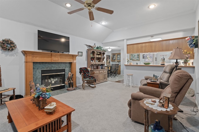 living room featuring a tiled fireplace, light colored carpet, vaulted ceiling, and ceiling fan