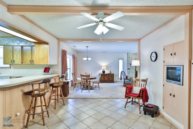 kitchen with ornamental molding, a textured ceiling, light colored carpet, ceiling fan, and hanging light fixtures