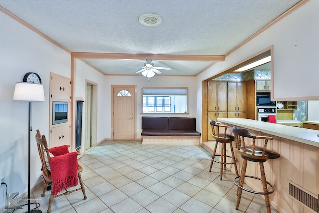 kitchen featuring black microwave, ceiling fan, oven, a textured ceiling, and light tile patterned floors