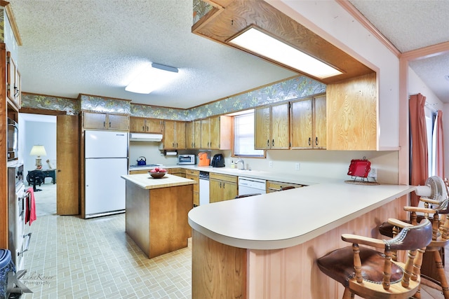 kitchen with white appliances, a kitchen breakfast bar, ornamental molding, a textured ceiling, and kitchen peninsula