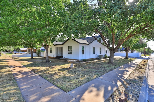 view of front of home featuring central AC unit, fence, and roof with shingles