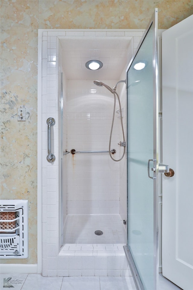 bathroom with tile patterned flooring, heating unit, and a shower with shower door