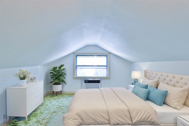 bedroom with vaulted ceiling, a textured ceiling, and a wall mounted AC