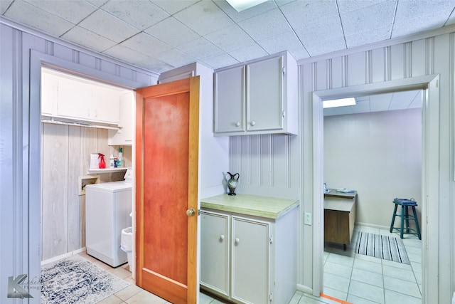 clothes washing area featuring wood walls, light tile patterned floors, cabinets, and washer / dryer