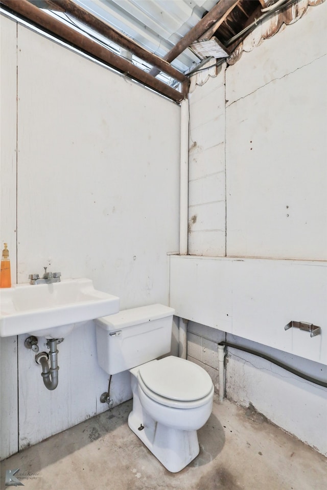 bathroom with sink, concrete flooring, and toilet