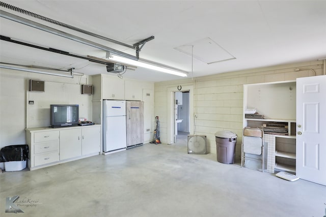 garage with white fridge and a garage door opener