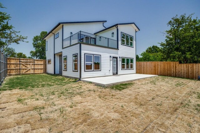 rear view of house featuring a balcony, a patio, and a yard