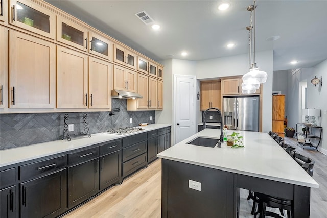 kitchen featuring sink, a breakfast bar, a kitchen island with sink, hanging light fixtures, and stainless steel appliances