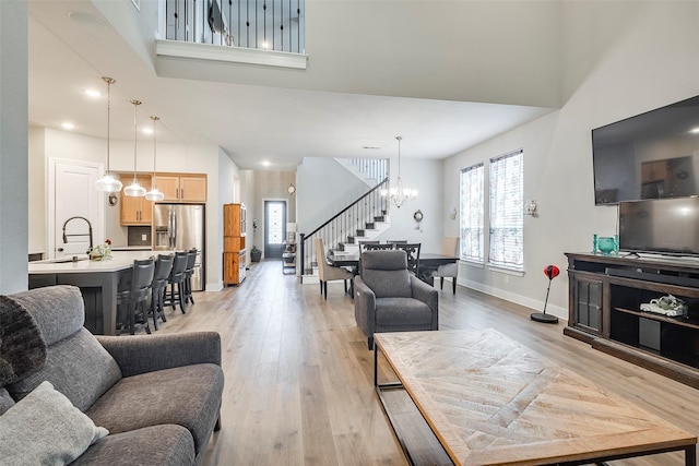 living room with sink, a notable chandelier, and light hardwood / wood-style floors