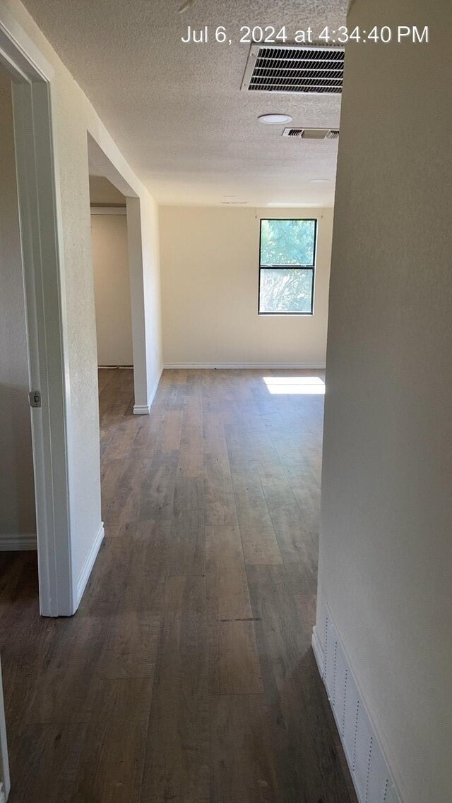 hallway with dark hardwood / wood-style floors and a textured ceiling