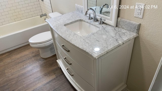 full bathroom featuring hardwood / wood-style flooring, toilet, vanity, and tiled shower / bath