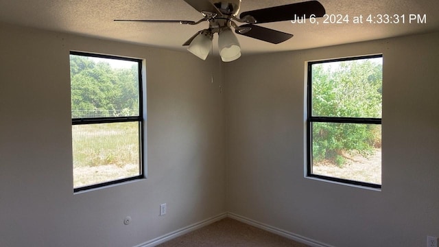 carpeted empty room featuring ceiling fan and a wealth of natural light