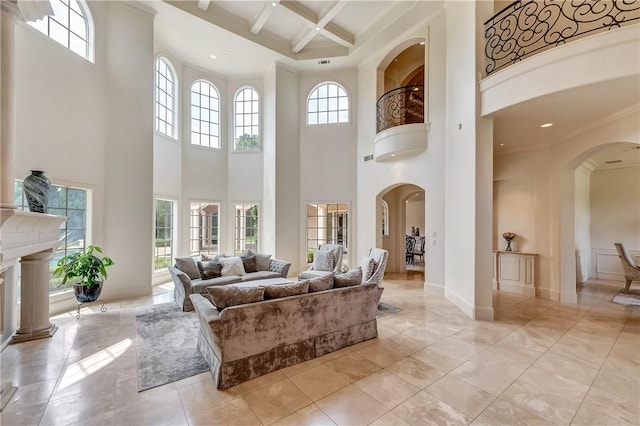 living room with arched walkways, coffered ceiling, ornamental molding, a fireplace, and beam ceiling