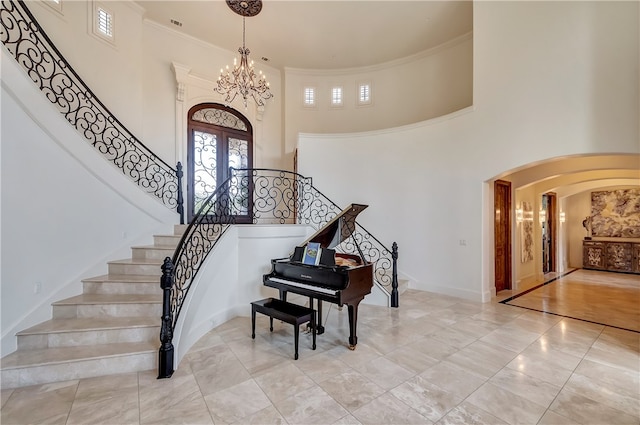 foyer entrance featuring an inviting chandelier, a high ceiling, light hardwood / wood-style flooring, and ornamental molding