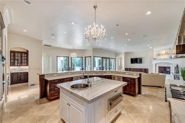 kitchen featuring a spacious island, a sink, open floor plan, hanging light fixtures, and a warming drawer