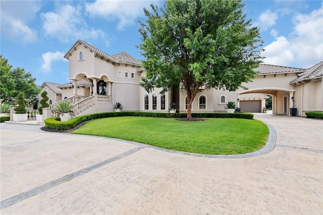 mediterranean / spanish-style house with driveway, a front yard, a tiled roof, and stucco siding