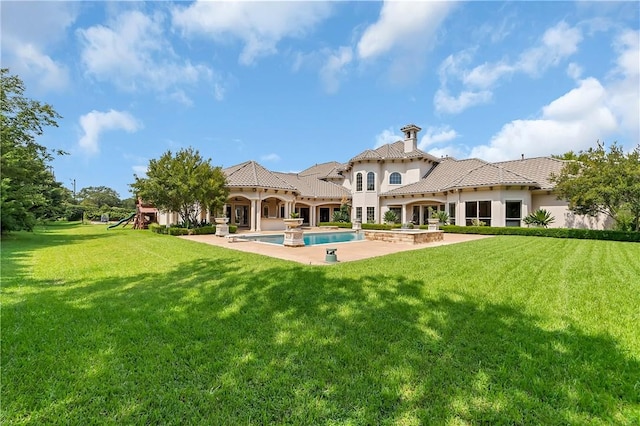 rear view of property featuring a playground, a lawn, a patio area, an outdoor pool, and a tiled roof