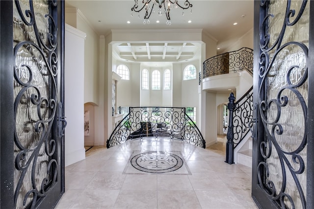 foyer entrance featuring an inviting chandelier, coffered ceiling, light tile patterned floors, and a towering ceiling