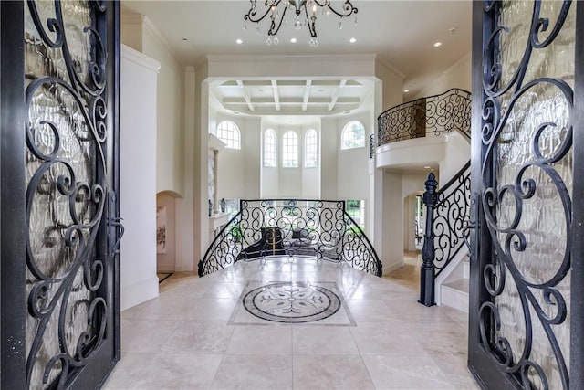 entryway with arched walkways, stairway, a towering ceiling, an inviting chandelier, and coffered ceiling