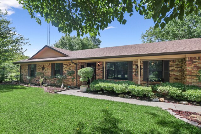 single story home featuring roof with shingles, a front lawn, and brick siding