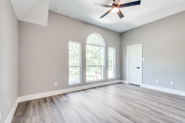 empty room featuring baseboards, plenty of natural light, and light wood finished floors