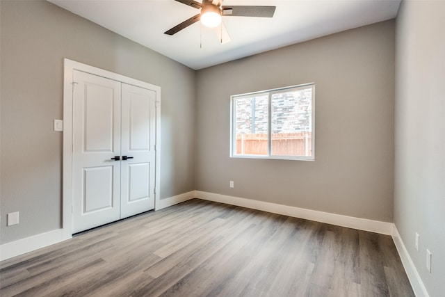 spare room featuring ceiling fan, light wood-style flooring, and baseboards