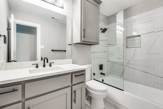 bathroom with enclosed tub / shower combo, visible vents, vanity, and toilet