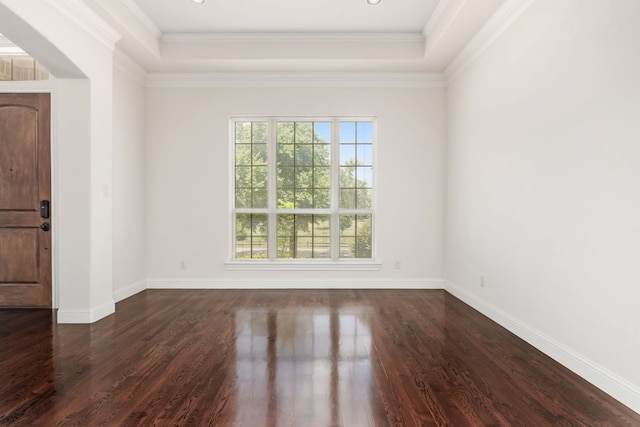 empty room featuring a tray ceiling, crown molding, and dark hardwood / wood-style floors