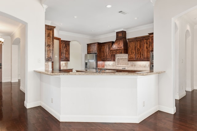 kitchen featuring custom exhaust hood, decorative backsplash, kitchen peninsula, and appliances with stainless steel finishes